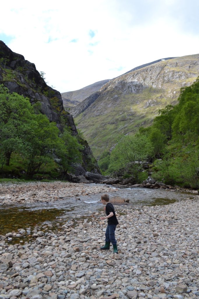 Child with autism throwing rocks by a stream in Scotland.