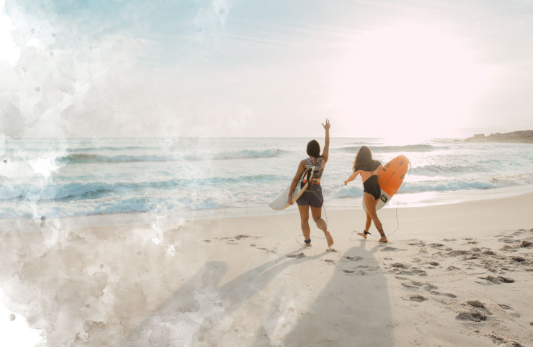 Two girls going into the sea with their surf tables