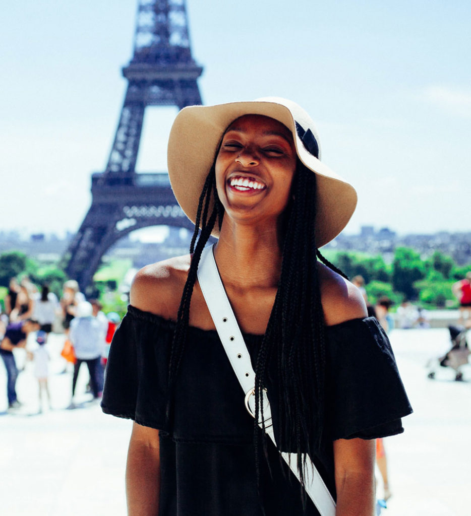 A woman smiling in front of the Eiffel Tower